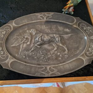 Jugendstil pladanj od cina s reljefom psa i fazana, oko 1900. godine, s dekorativnim biljnim motivima i izraženom umjetničkom obradom.